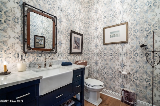 5151 Creswell Dr, Leland, NC 28451 - half bathroom with vanity, wood finished floors, baseboards, toilet, and wallpapered walls