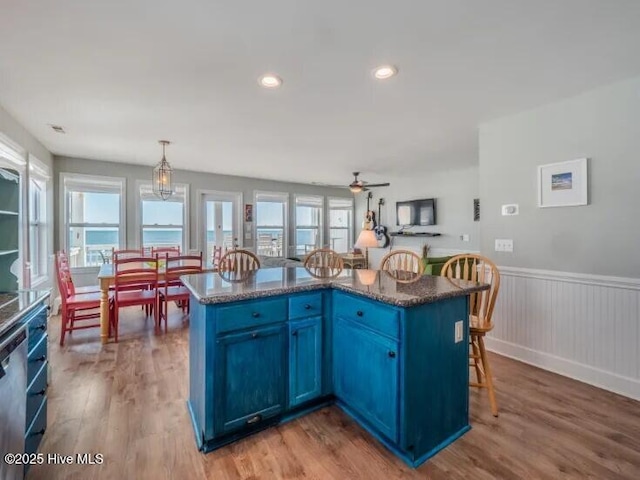 kitchen featuring blue cabinets, a kitchen bar, and wood finished floors