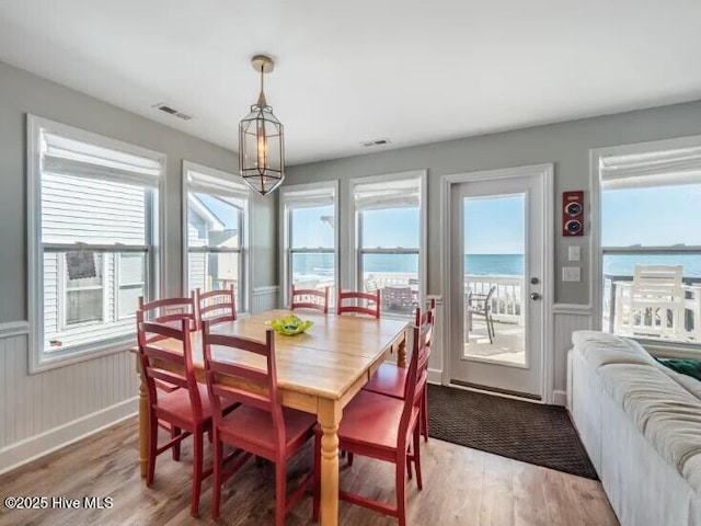 dining area featuring a wainscoted wall, visible vents, and wood finished floors