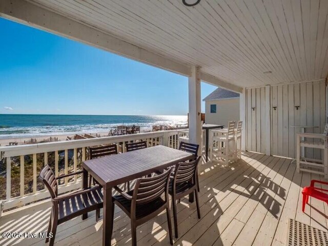 wooden deck featuring a beach view and a water view