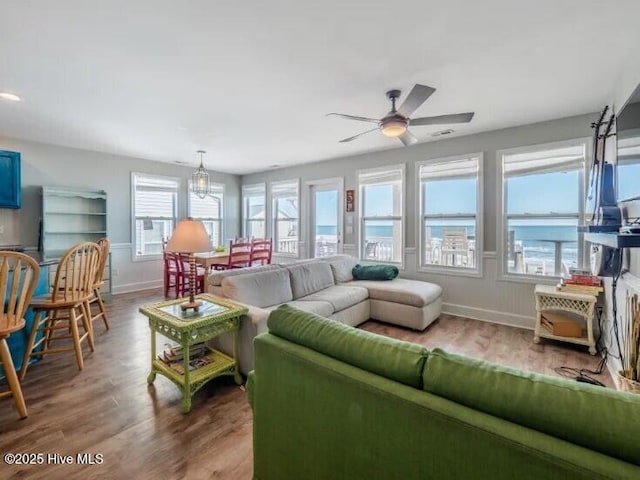 living area featuring a ceiling fan, wood finished floors, and baseboards