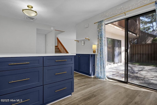 kitchen with visible vents, blue cabinetry, light countertops, and wood finished floors