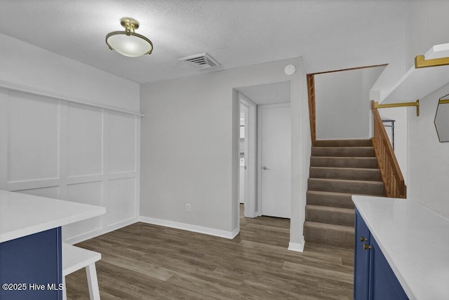 interior space with visible vents, baseboards, stairway, dark wood-style floors, and a textured ceiling