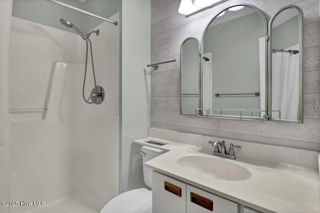 bathroom featuring wooden walls, a shower stall, vanity, and toilet