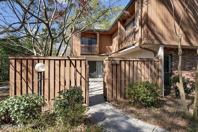 view of side of home with fence, brick siding, and a gate