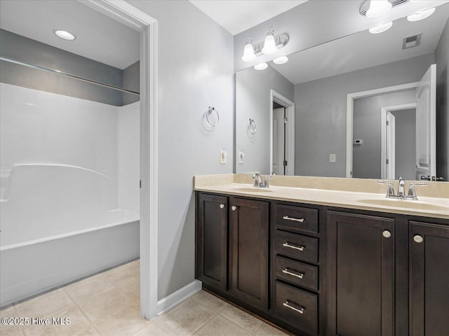 bathroom featuring double vanity, washtub / shower combination, and baseboards