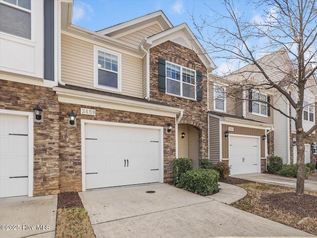 view of property with an attached garage, stone siding, and driveway