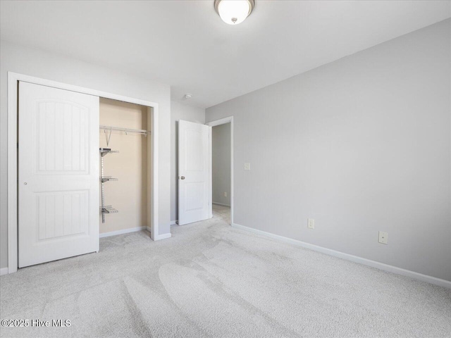 unfurnished bedroom featuring light colored carpet, baseboards, and a closet