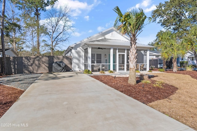 view of front of home with fence, concrete driveway, a ceiling fan, and a sunroom