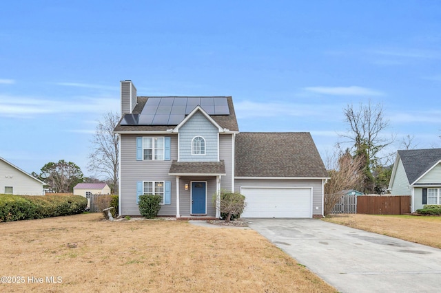 traditional-style home featuring fence, solar panels, an attached garage, concrete driveway, and a front lawn