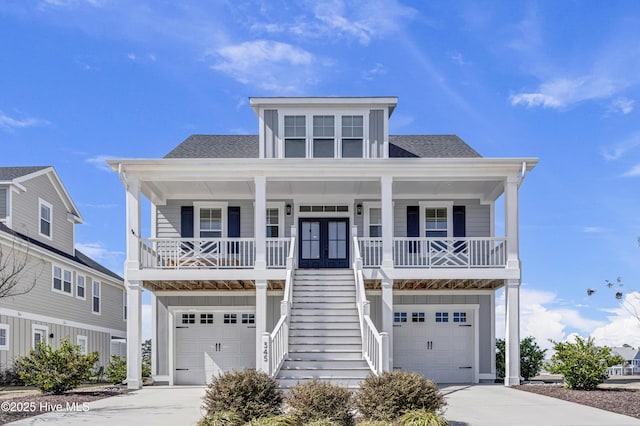 beach home with covered porch, an attached garage, concrete driveway, and stairs