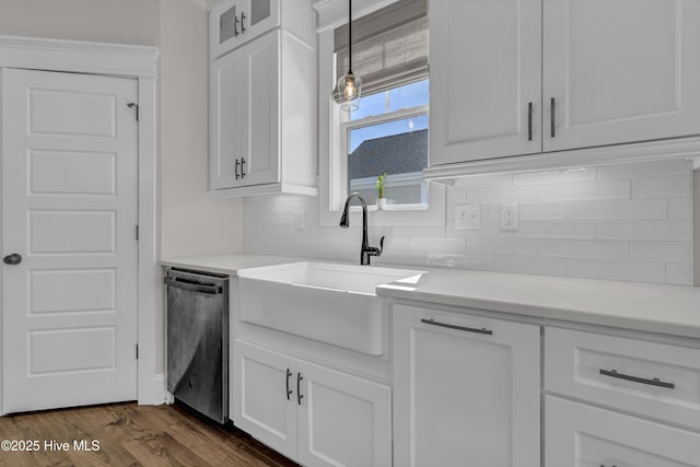 kitchen with tasteful backsplash, dark wood-type flooring, stainless steel dishwasher, white cabinetry, and a sink