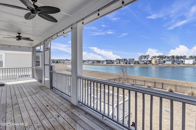 wooden terrace featuring a water view, ceiling fan, and fence