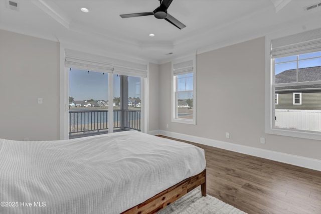 bedroom with wood finished floors, visible vents, baseboards, access to exterior, and a raised ceiling