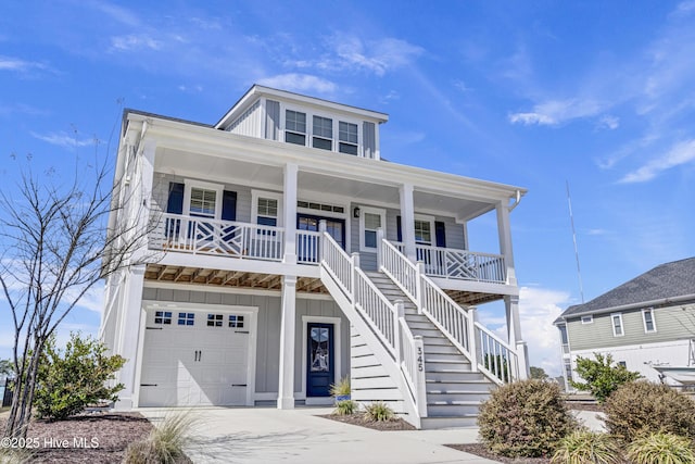 coastal home featuring an attached garage, covered porch, stairs, concrete driveway, and board and batten siding