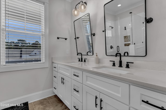 full bathroom featuring a sink, baseboards, double vanity, and a shower stall