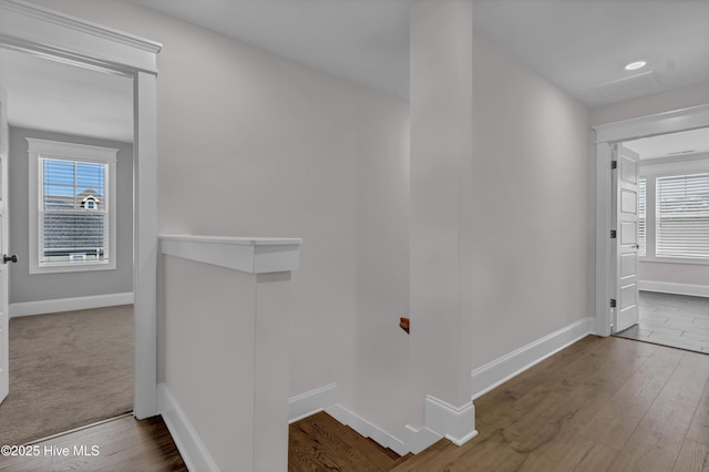 corridor featuring baseboards, an upstairs landing, and wood finished floors