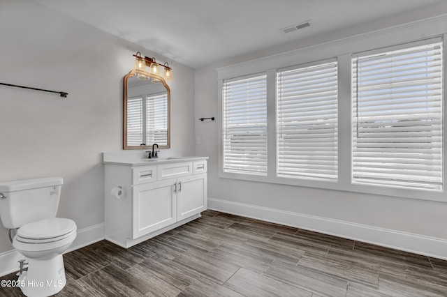 bathroom with visible vents, baseboards, toilet, and vanity