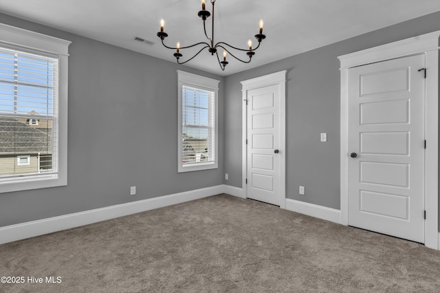 interior space with plenty of natural light, baseboards, visible vents, and a chandelier