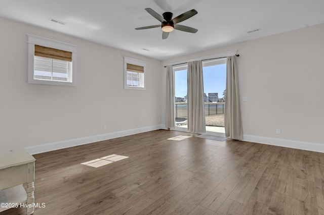 unfurnished room featuring visible vents, baseboards, ceiling fan, and wood finished floors