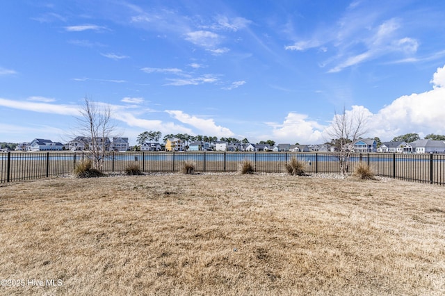 view of yard featuring a residential view, a water view, and fence