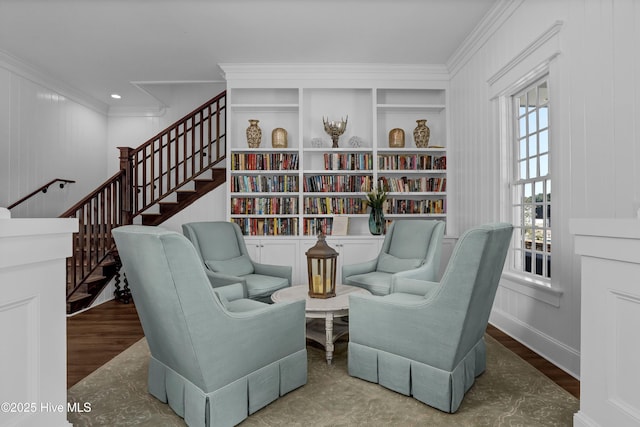 living area with built in features, stairway, wood finished floors, and ornamental molding