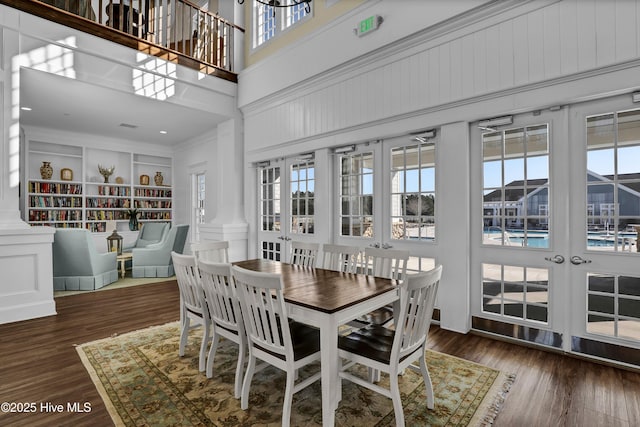 dining area with built in shelves, wood finished floors, and a towering ceiling