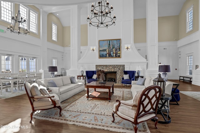 living area with a stone fireplace, a decorative wall, and a notable chandelier