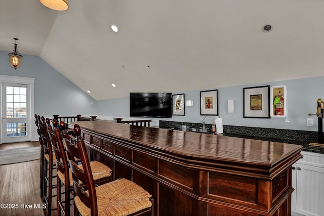 bar with a dry bar, lofted ceiling, and wood finished floors