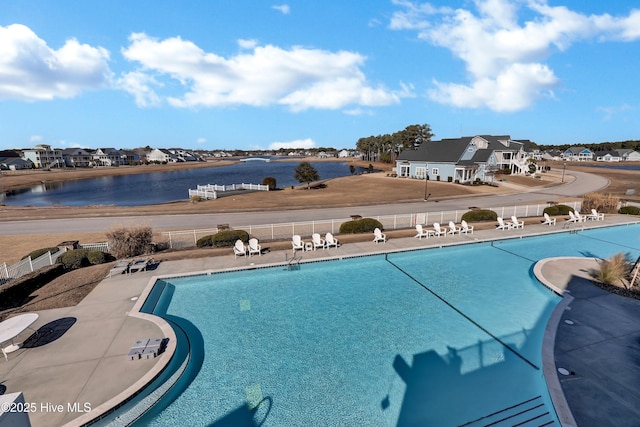 pool featuring a patio area, fence, and a water view