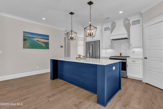 kitchen with a kitchen island, ornamental molding, custom range hood, appliances with stainless steel finishes, and a chandelier