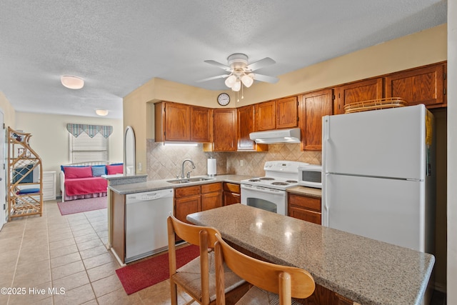 kitchen featuring a ceiling fan, under cabinet range hood, a sink, white appliances, and decorative backsplash