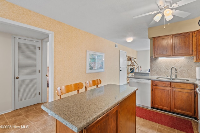 kitchen featuring brown cabinets, a sink, tasteful backsplash, a center island, and dishwasher