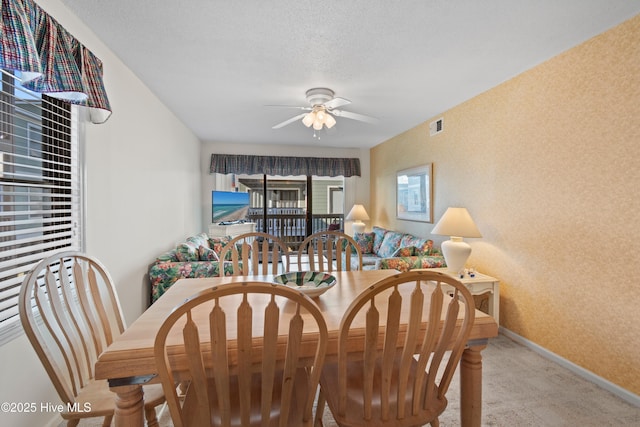 dining area with visible vents, a ceiling fan, a textured ceiling, baseboards, and light colored carpet