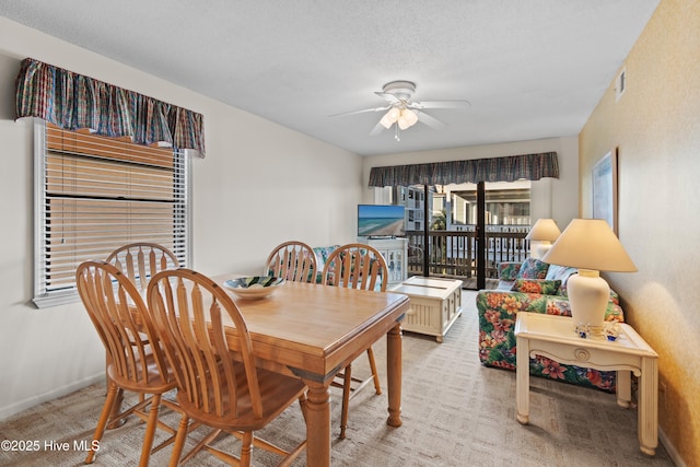 dining area featuring baseboards, visible vents, ceiling fan, a textured ceiling, and light carpet