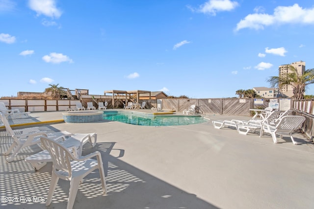 view of pool with a patio, fence, and a pool with connected hot tub