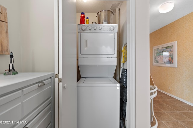 laundry area with laundry area, stacked washer and dryer, baseboards, and tile patterned floors