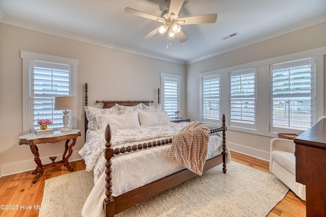 bedroom featuring visible vents, crown molding, baseboards, and wood finished floors