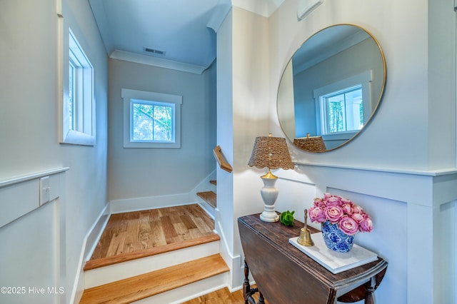 staircase with visible vents, crown molding, baseboards, and wood finished floors