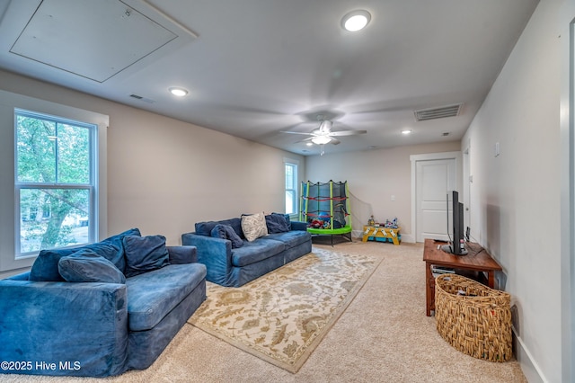 living area featuring baseboards, visible vents, attic access, and ceiling fan