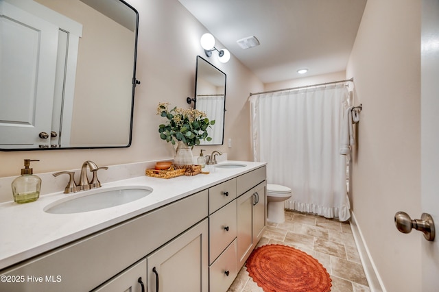 full bath with double vanity, toilet, baseboards, and a sink