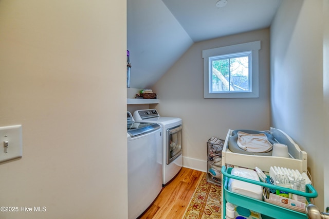 laundry area featuring baseboards, wood finished floors, laundry area, and washer and clothes dryer