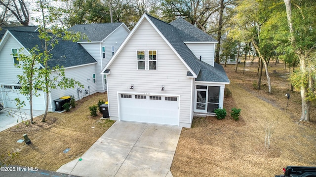 view of front facade with an attached garage, central AC unit, driveway, and a shingled roof