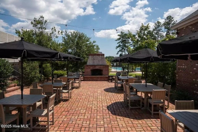 view of patio with outdoor dining area, fence, and an outdoor brick fireplace