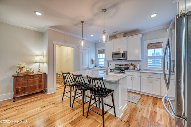 kitchen featuring light wood-style flooring, white cabinetry, stainless steel appliances, and ornamental molding