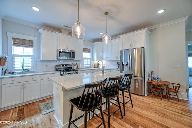 kitchen with ornamental molding, light wood-style flooring, a sink, stainless steel appliances, and white cabinets