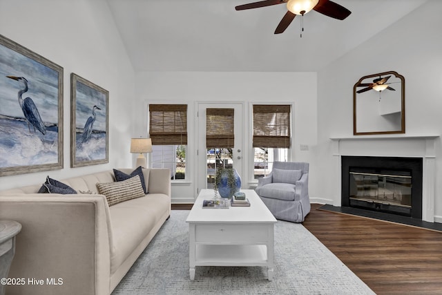 living room featuring a glass covered fireplace, lofted ceiling, wood finished floors, and ceiling fan