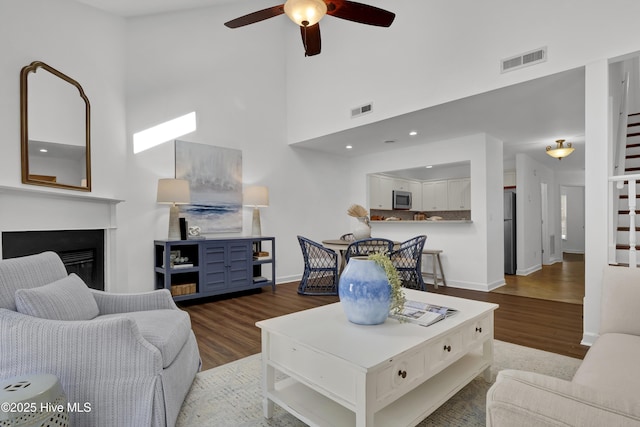 living room with visible vents, wood finished floors, and ceiling fan