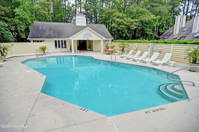 community pool featuring a storage structure, a patio, an outdoor structure, and fence