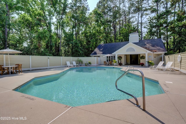 pool with an outbuilding, a storage structure, a patio, and fence